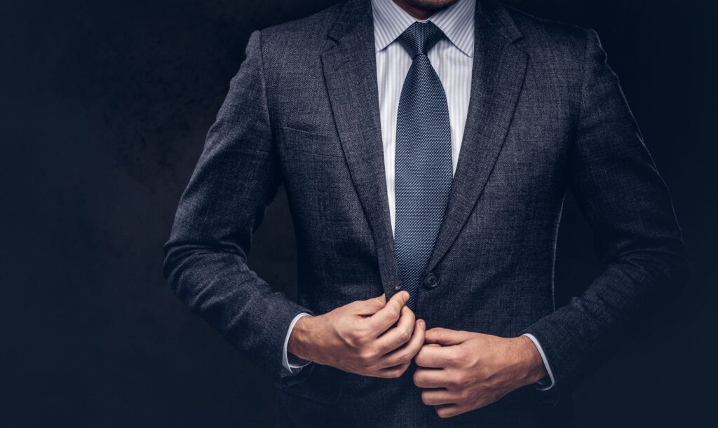 cropped-portrait-successful-businessman-buttoning-his-elegant-suit-isolated-dark-background-scaled